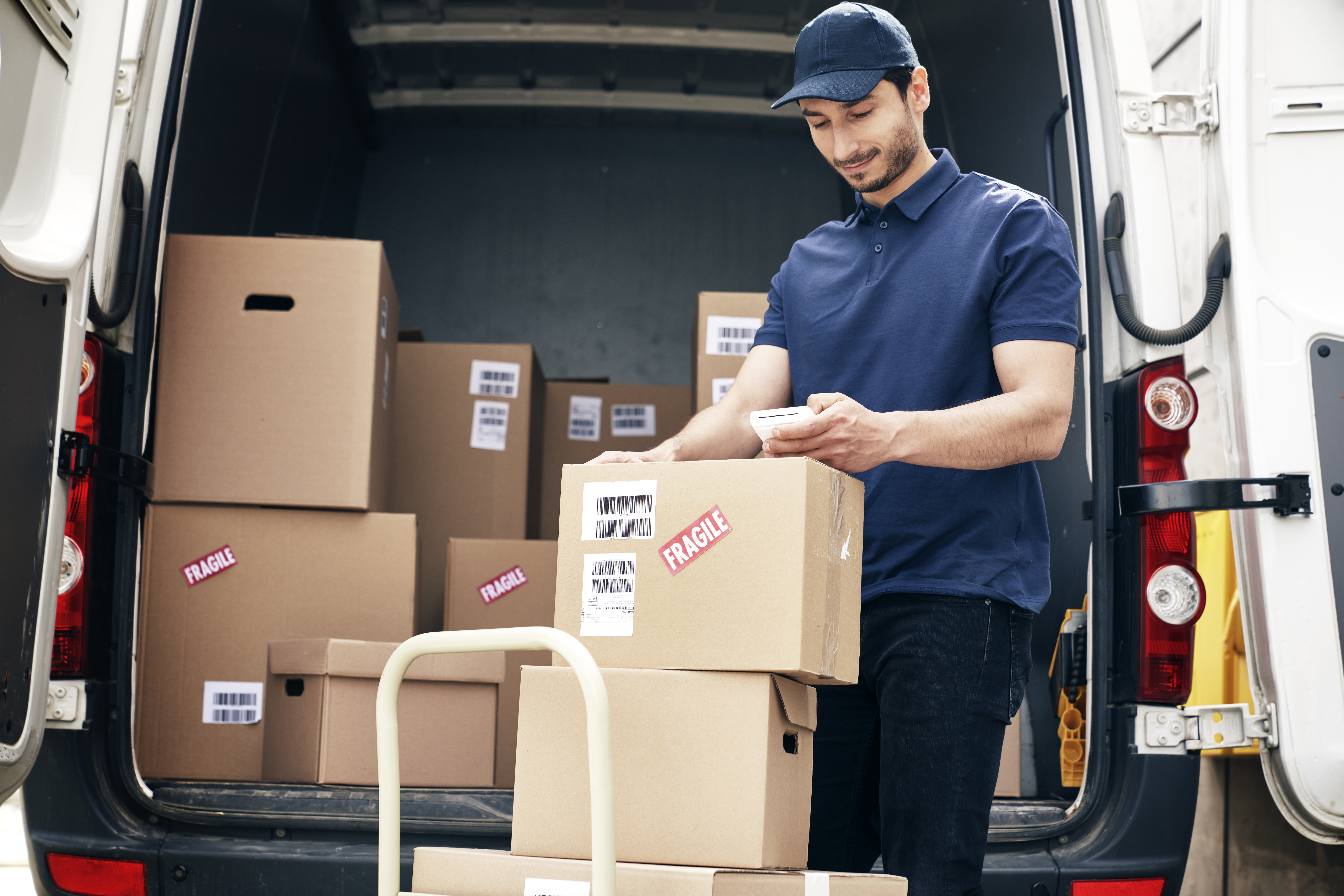 smiling-courier-checks-parcels-on-the-hand-truck-NBYJC3Q smiling-courier-checks-parcels-on-the-hand-truck-NBYJC3Q